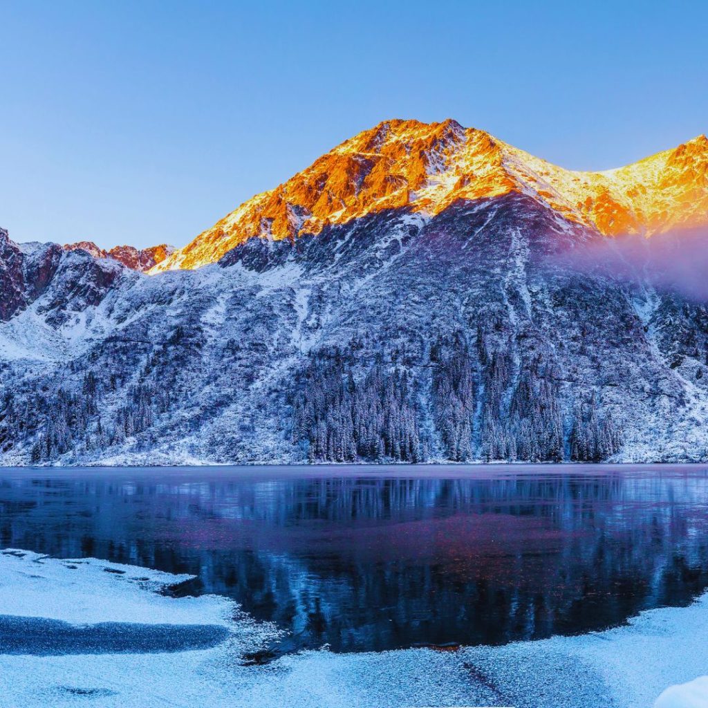 sunlit mountains in the winter with snow and an icy river